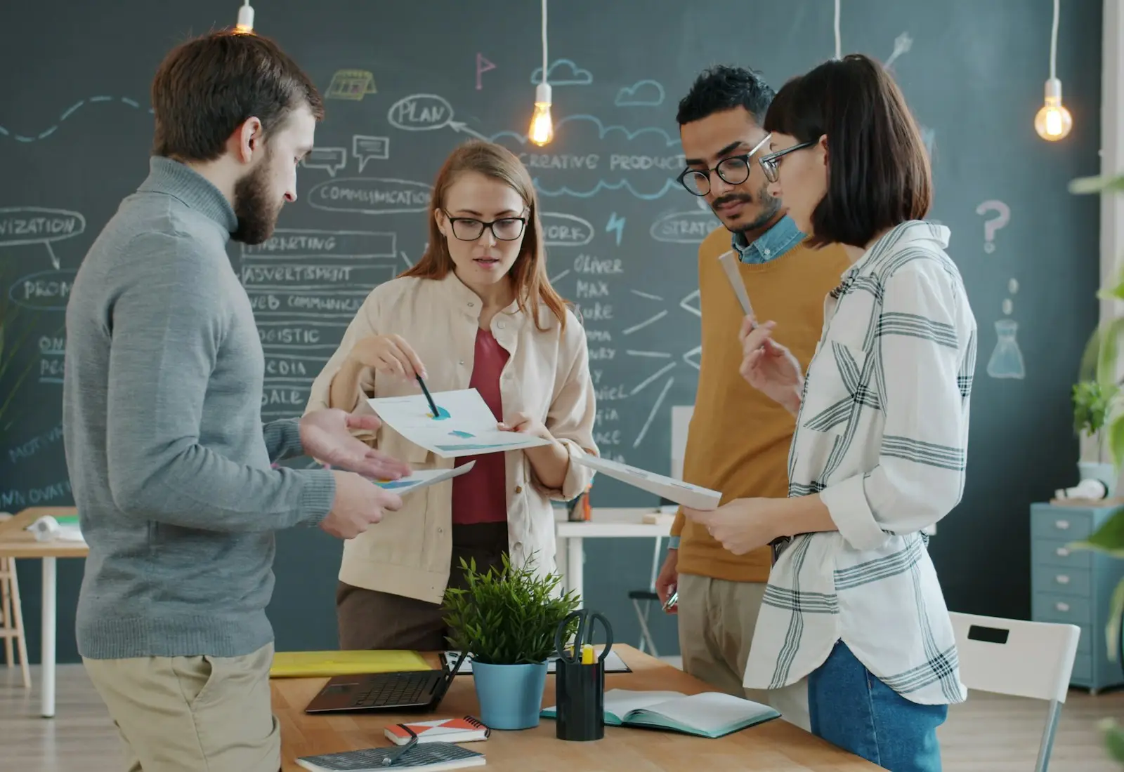 Equipo creativo revisando ideas y documentos alrededor de una mesa de trabajo