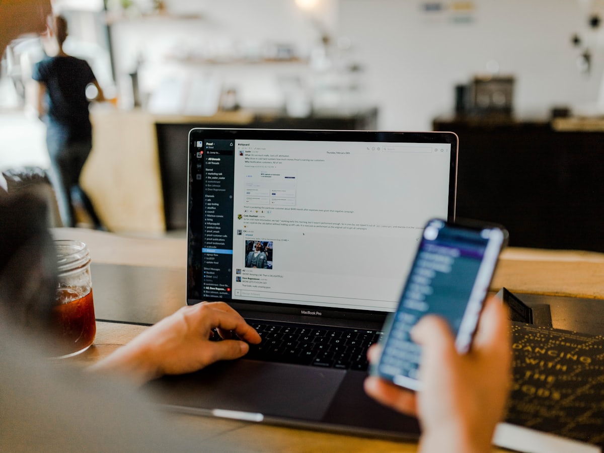 Persona gestionando publicaciones desde un portátil y un móvil