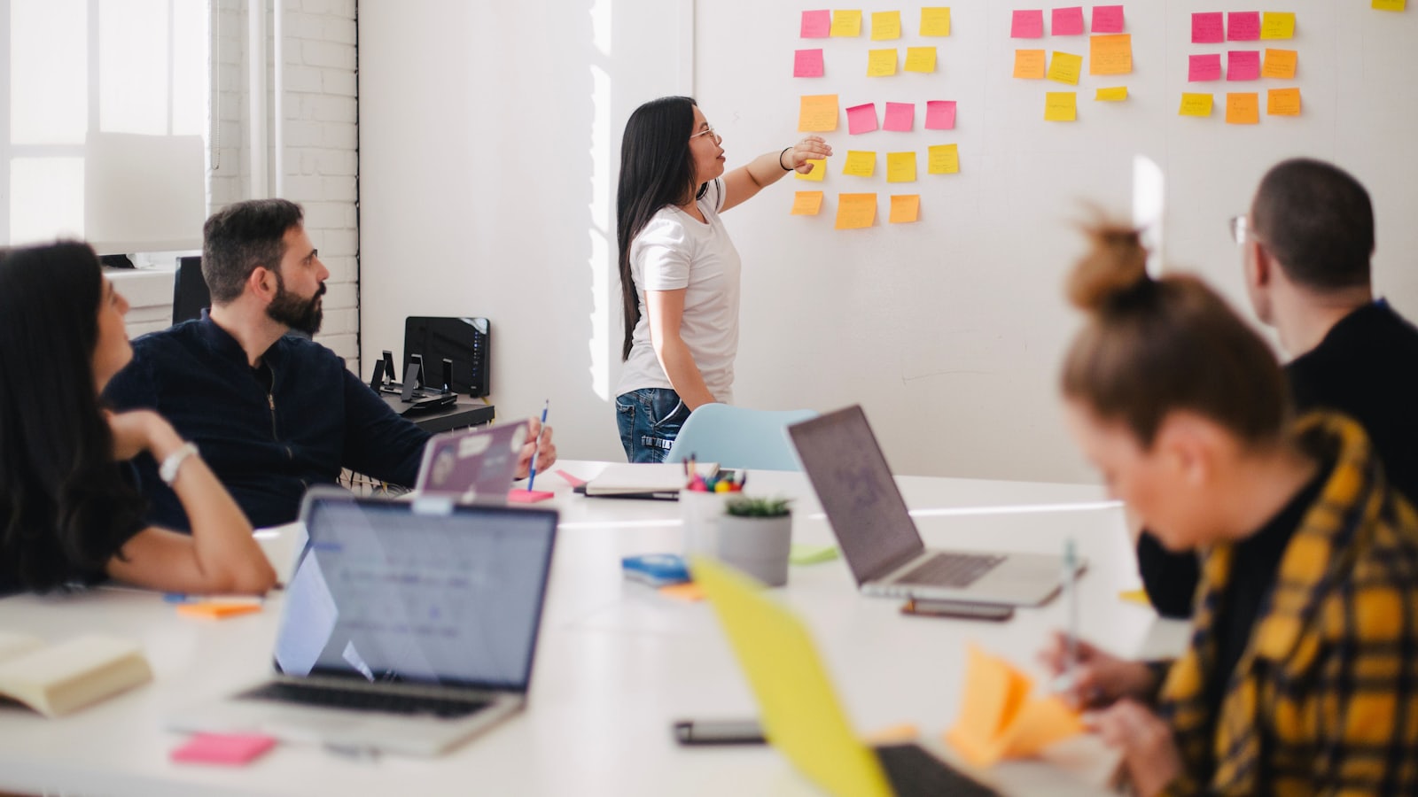 Sesión de trabajo de un equipo creativo alrededor de una pared de notas adhesivas